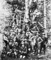 1926 р. Лісові чорти — старші пластуни зі Львова під час будівництва першої пластової оселі. Роман Шухевич зліва від гітариста. Ґорґани, схили гори Сехліс (фото Володимир Мурського, який сиди